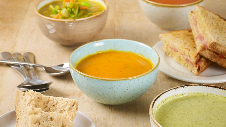 A table filled with bowls of heart-warming soup with crusty bread.